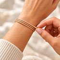 “Treat yourself to a little touch of gold. Every day can have its own sparkle.” Sometimes a single detail is enough to give an entire outfit a new charm. The gold magnetic bracelet Variace from the Power of Colors collection captivates with its warm shade, delicate cord texture, and the ability to change its look according to your mood. Wrap it around your wrist and let the individual rows sit neatly side by side, cross them lightly, or create a looser arrangement. One piece of jewelry gives you room for your own variations. On its own, it looks delicate and elegant. Combined with mineral bracelets, it adds a bright, more festive accent to your set. It stands out beautifully next to white, cream, brown, and black. The magic lies in the cord itself It’s not just about the magnetic clasp. The magnetic parts of the cord cling together when wrapped, so you don’t need to fasten a tiny lobster clasp or search for a loop. Simply wrap the cord around your wrist, place its parts together, and adjust the position of the ends. You can adjust the size and arrangement of the rows within the range allowed by the total length of 51 cm. The number of wraps depends on the circumference of your wrist. Gold – the color of light and exceptional moments The golden shade evokes sunlight, warmth, and moments worth keeping. In the Power of Colors collection, you can embrace it as a personal symbol of joy, abundance, and awareness of your own worth. Wear it as a small reminder that you are allowed to treat yourself to something beautiful even on an ordinary day. Or give it to someone you want to tell: “You are precious to me.” One piece of jewelry, more possibilities On your wrist, you can create a multi-row bracelet according to your taste. The length of the cord also offers the possibility of trying it as a short necklace — if your neck circumference allows comfortable wear and sufficient overlap of the magnetic parts. Change its look according to your outfit and the occasion. One time a subtle accessory, another time a more striking part of your favorite combination. Why you’ll love it Variable look: arrange the individual rows as you like. Easy to put on: no classic clasp or tiny loops. Adjustable circumference: by wrapping and overlapping the cord. Delicate design: the approximately 2 mm cord stands out even in multiple rows. Warm golden shade: for everyday elegance and more festive moments. Easy to combine: with watches, mineral bracelets, and other accessories. Who it is suitable for For lovers of warm shades, delicate jewelry, and accessories that can be adapted to personal style. It suits both women and men who like to wear golden tones. It also makes a lovely gift — the recipient can choose how to wear it and what personal meaning to give it. How to put on the bracelet Wrap the cord around your wrist so that it fits comfortably. Place the magnetic parts together and let them cling. Adjust the individual rows and the position of the ends. Before wearing, check that the overlap holds well. When taking it off, gently separate the parts without pulling sharply on the ends. Material and dimensions Cord color: golden shade. Total length: 51 cm. Cord thickness: approximately 2 mm. Design: magnetic cord with a textile surface. Ends: metal, in gold color. Size when worn: adjustable according to wrapping and overlap. Package contents: 1 piece. The designation “golden” describes the color finish, not manufacture from precious metal. Bracelet care Put it on last and take it off first. Protect the cord and ends from perfume, cosmetics, cleaning agents, and prolonged soaking. Remove the bracelet before bathing, sports, and sleeping. Clean with a soft dry or slightly damp cloth and let it air dry away from direct sunlight. Separate the magnetic parts gently. Magnetism serves for adhesion and arrangement of the cord. The bracelet is a fashion accessory, not a medical aid. Power of Colors – your style, your variations.